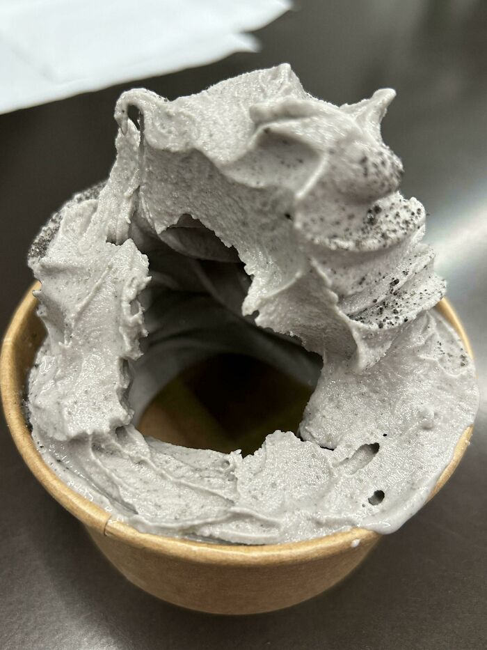 Gray ice cream in a cup with deceptive hollow center highlighting food scams.