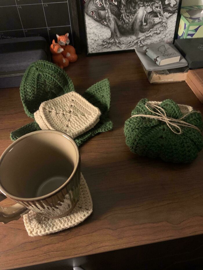 Green and beige crochet masterpieces including coasters and small pouches displayed on a wooden surface.