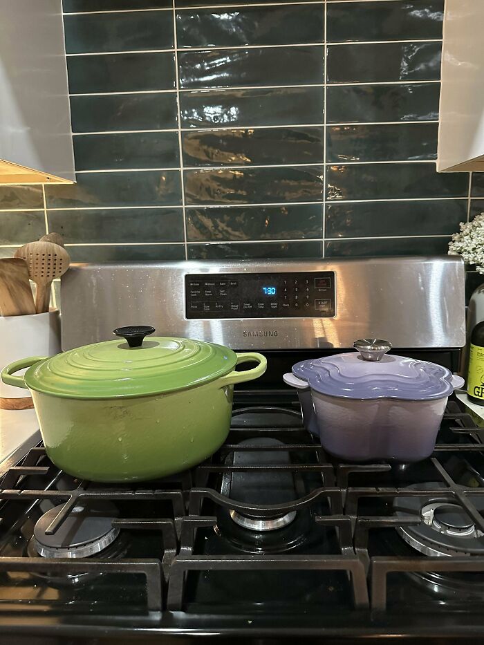 Two colorful pots on a stove, showcasing a thrifting find with a green and a purple pot against a tiled backsplash.