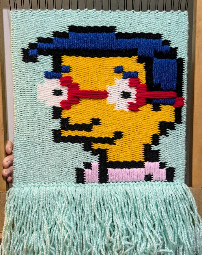 Cross-stitch art depicting a popular 90s cartoon character with red glasses and blue hair.