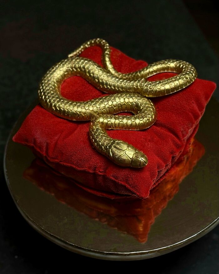 Golden snake-shaped edible decoration on a red velvet cushion bake, showcasing one of the most incredible bakes.