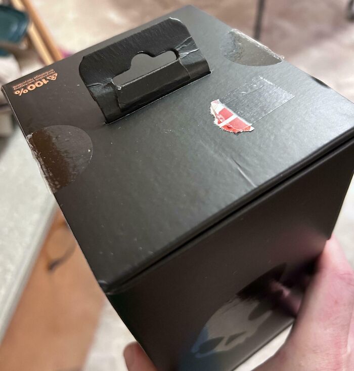 Black box with poorly applied stickers, showcasing online shopping fails.