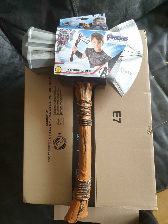 Toy hammer labeled "Stormbreaker" looking different from expectations, atop a cardboard box, illustrating online shopping fails.