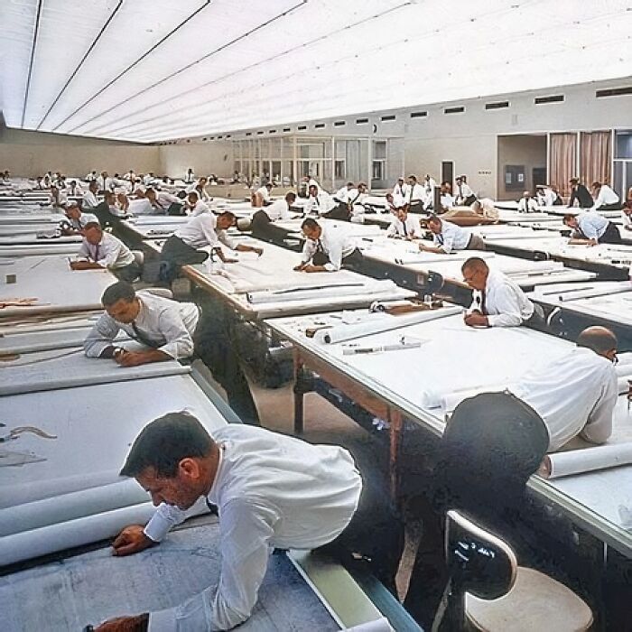 Historic photo of engineers in a large drafting room, illustrating teamwork and precision from the past.