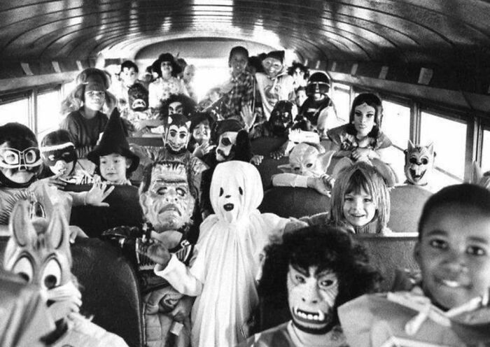 A group of children in Halloween costumes on a vintage school bus, showcasing history cool kids in the past.