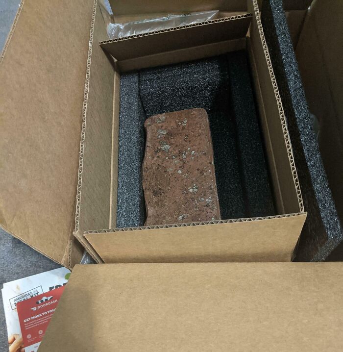 Brick inside a cardboard box, illustrating a funny online shopping scam or fail.
