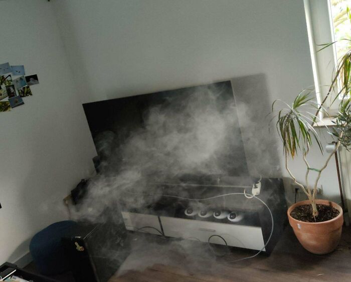 Smoke spreading from an electronic device in a living room, illustrating a tech support worker's unexpected malfunction challenge.