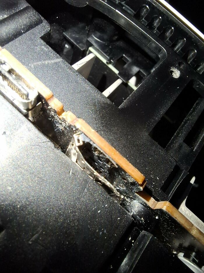 Close-up of damaged electronic circuit board inside a device, illustrating challenges faced by tech support workers.