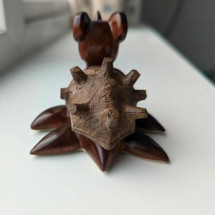 Wooden sculpture of a hedgehog with intricate details, showcasing a unique woodworking project on a white surface.