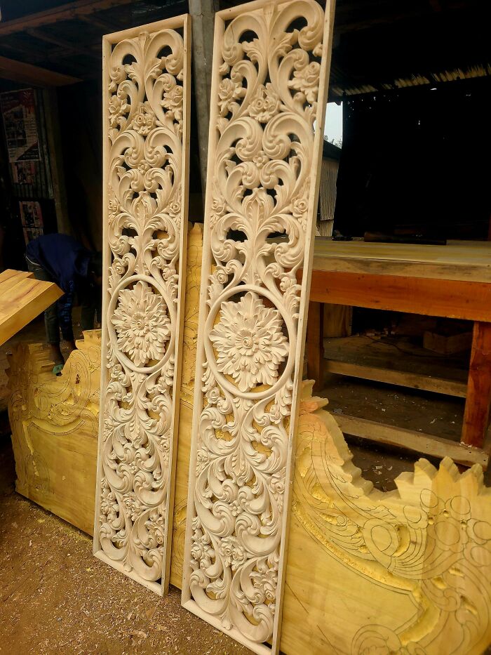 Intricate woodworking project featuring detailed carved wooden panels leaning against a workbench.