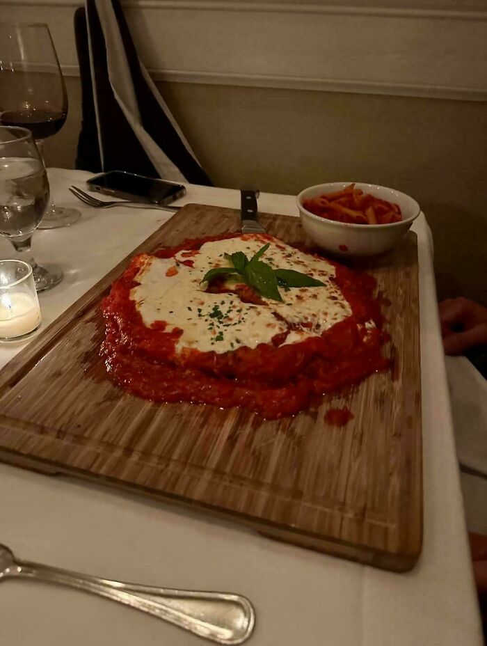 Pasta served on a wooden cutting board with sauce spread messily, illustrating ridiculous food presentation in restaurants.