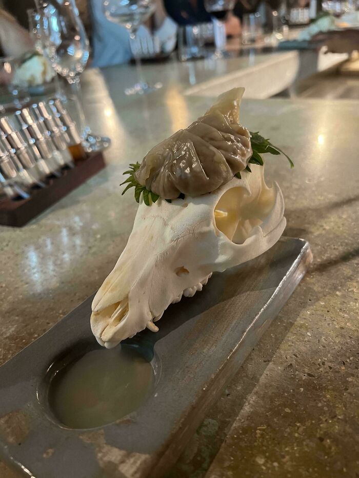 Unique and ridiculous food presentation in restaurants featuring a skull plate with a dumpling and dipping sauce.