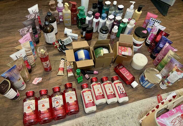 Assorted beauty products found while dumpster diving, including lotions and bottles, displayed on a wooden floor.