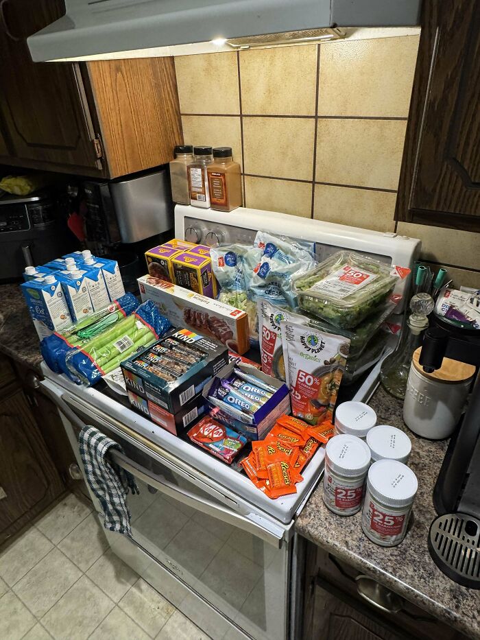 Dumpster diving success with a variety of packaged food items displayed on a kitchen stove.