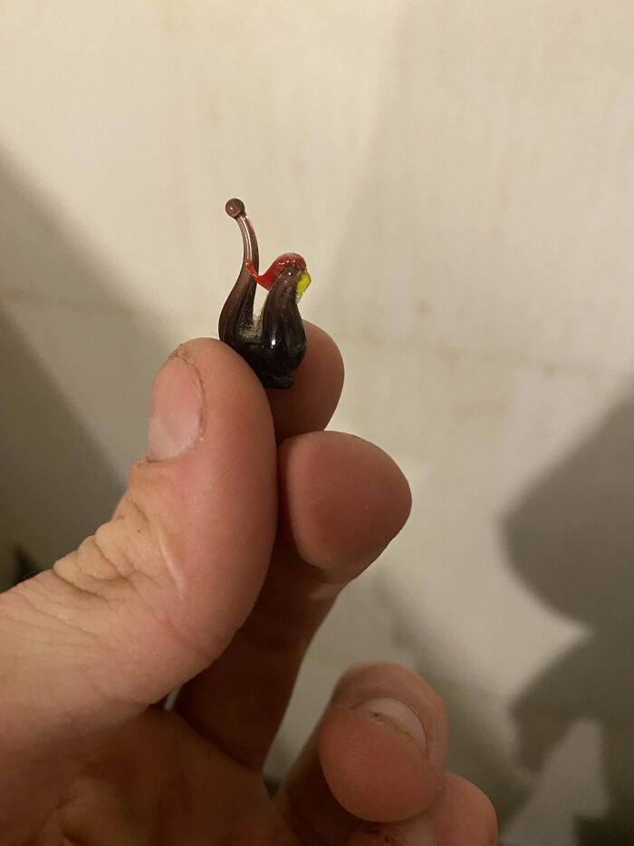 Hand holding a small found object, resembling a tiny glass ornament, from a successful dumpster diving trip.