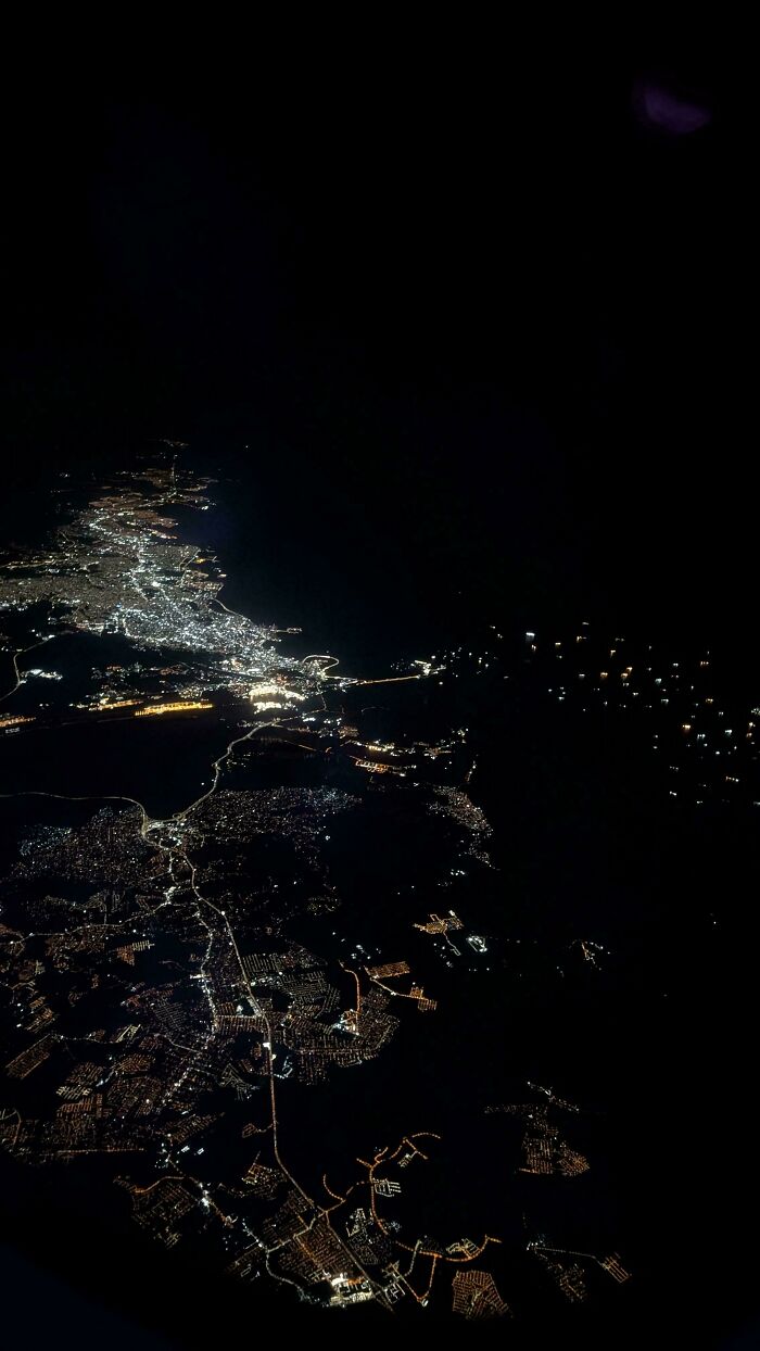 Aerial view of a city at night displaying a network of illuminated streets and buildings for mildly interesting observation.
