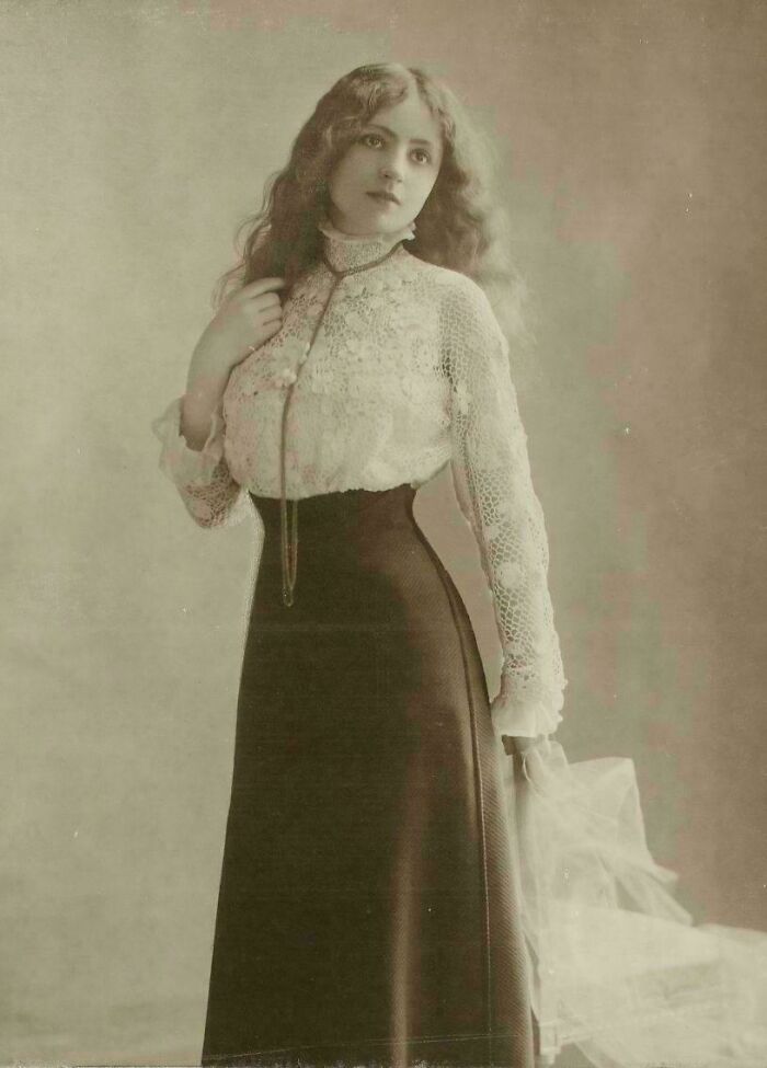 Victorian era woman in lace blouse and long skirt, posing elegantly.