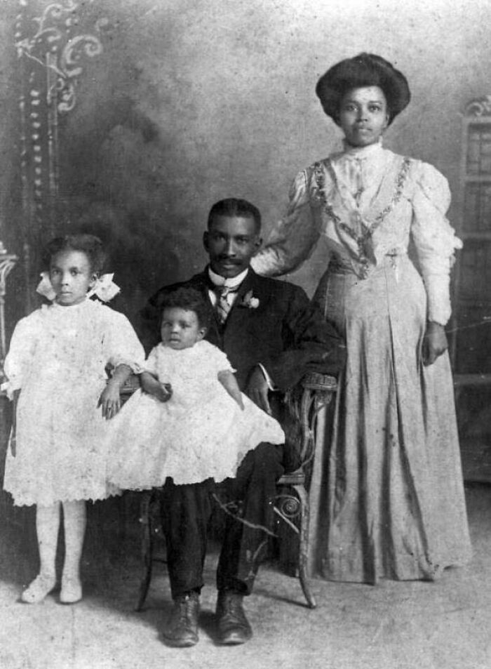 Victorian-era family portrait with parents and two children in formal attire.