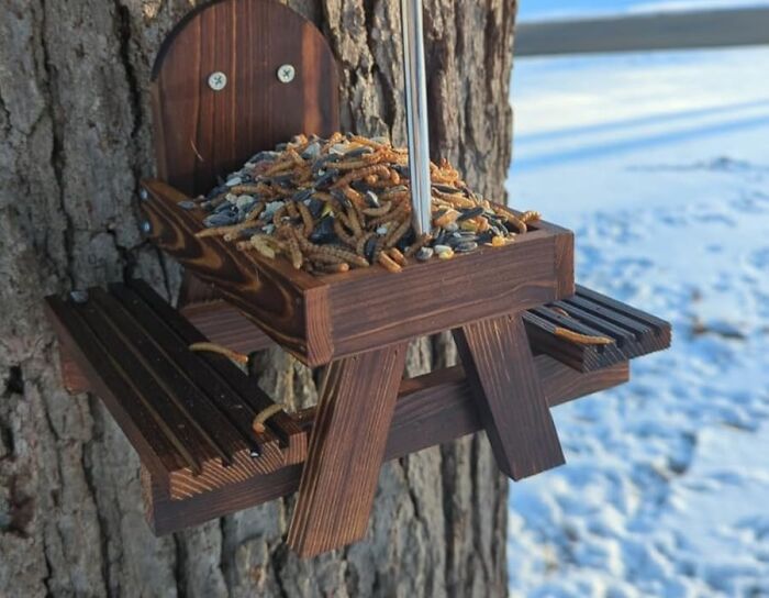 Squirrel feeder shaped like a picnic table, attached to a tree, showcasing one of the funniest Amazon finds.