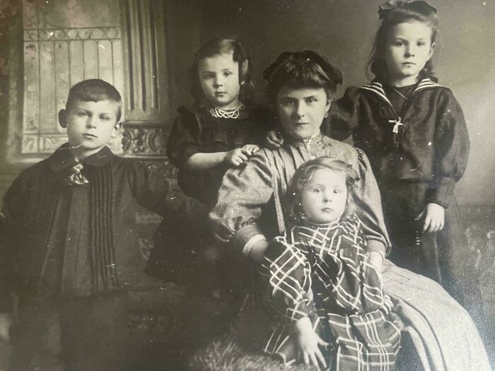 Victorian era family portrait with a woman and four children in period clothing, highlighting historical attire and expressions.