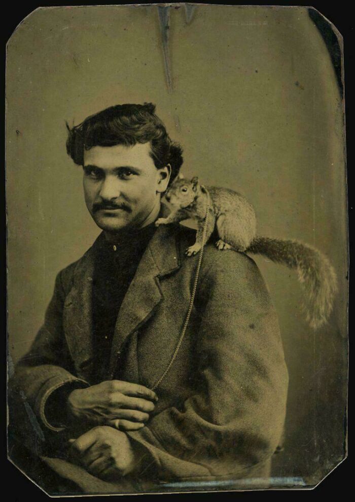 A man from the Victorian era with a squirrel on his shoulder, wearing a suit, and sporting a mustache.