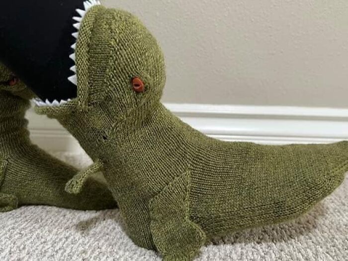 Knitted dinosaur-shaped slippers on carpet, showcasing one of the funniest Amazon finds.