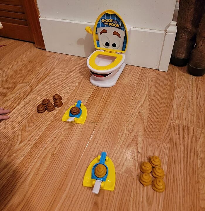 Toy toilet game with p**p pieces on a wooden floor, illustrating one of the funniest Amazon finds.