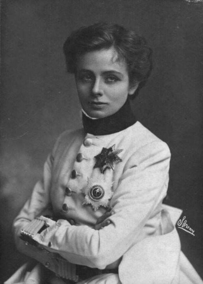 Victorian era woman in formal attire, wearing decorative medals, with a poised expression.