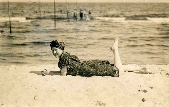 Woman in Victorian era swimsuit lying on the beach, enjoying the sun by the sea.
