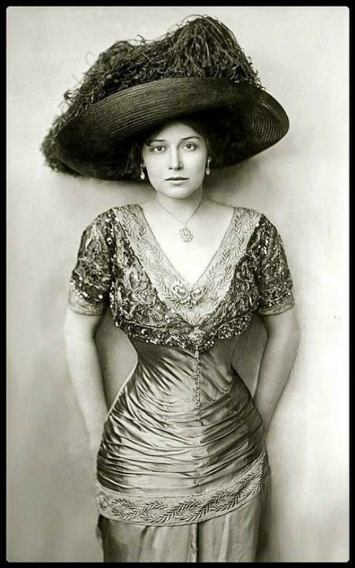 Victorian era woman in detailed dress and large hat, showcasing historical fashion.