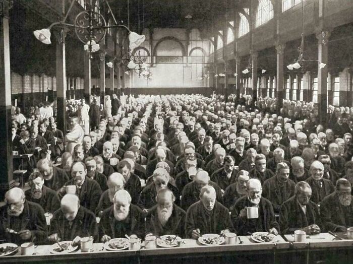 Victorian era dining hall filled with men seated at long tables.