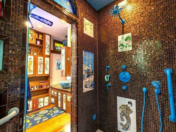 Bathroom with brown tile walls and blue fixtures, decorated with colorful art tiles showcasing awful taste but great e*******n.