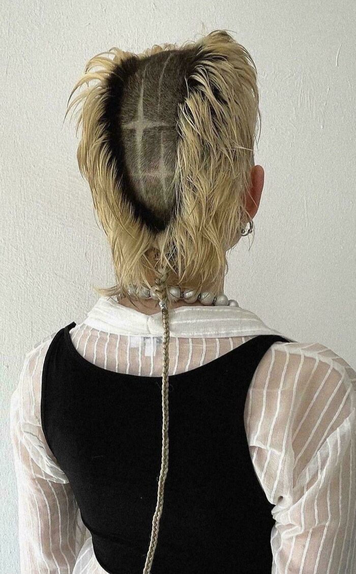 Unconventional hairstyle with a shaved cross design and a long braided ponytail, an example of awful taste but great e*******n.
