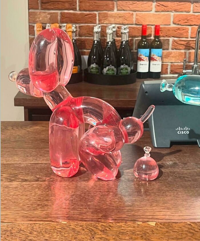 Transparent pink balloon dog sculpture designed to look like it is peeing, showcasing awful taste but great e*******n.