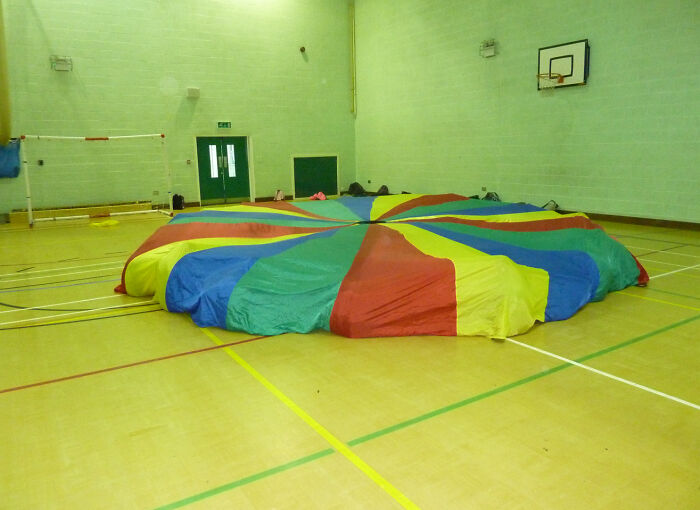 Colorful parachute spread out in a gym, evoking old-school memories.