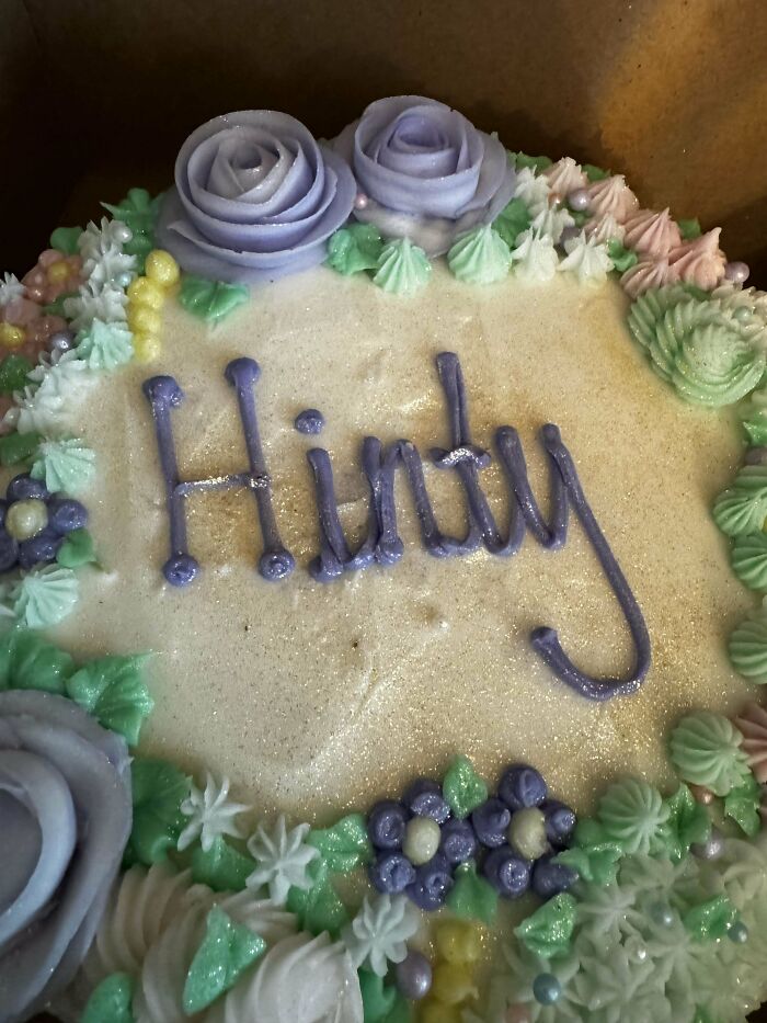 Cake with icing spelling "Hinny," surrounded by floral decorations; an example of hilarious misunderstandings.