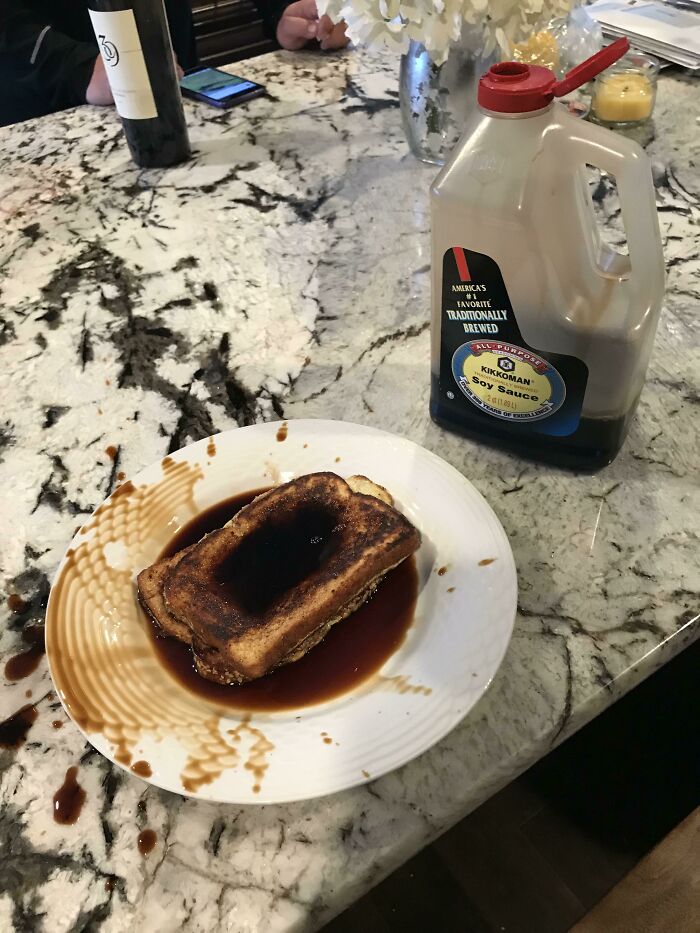 Soy sauce mistakenly poured over French toast, showcasing a hilarious misunderstanding on a marble counter.