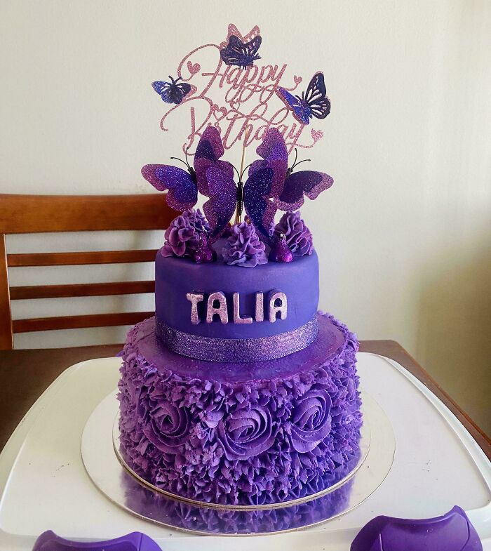 Purple birthday cake decorated with glittery butterflies and intricate floral frosting, an incredible bake worthy of spotlight.