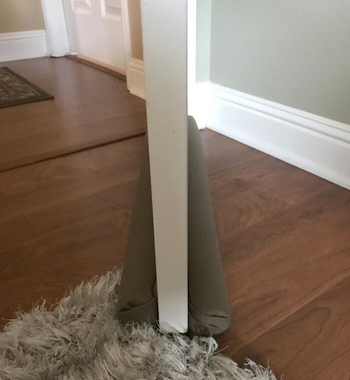Door draft stopper on hardwood floor for simple home DIY solution.