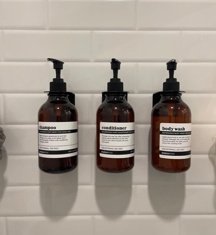 Wall-mounted shampoo, conditioner, and body wash bottles on a tiled bathroom wall for easy home DIY organization.
