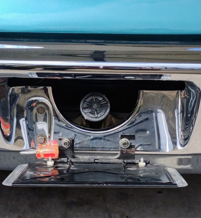 Vintage car fuel cap hidden behind chrome bumper, evoking childhood memories.