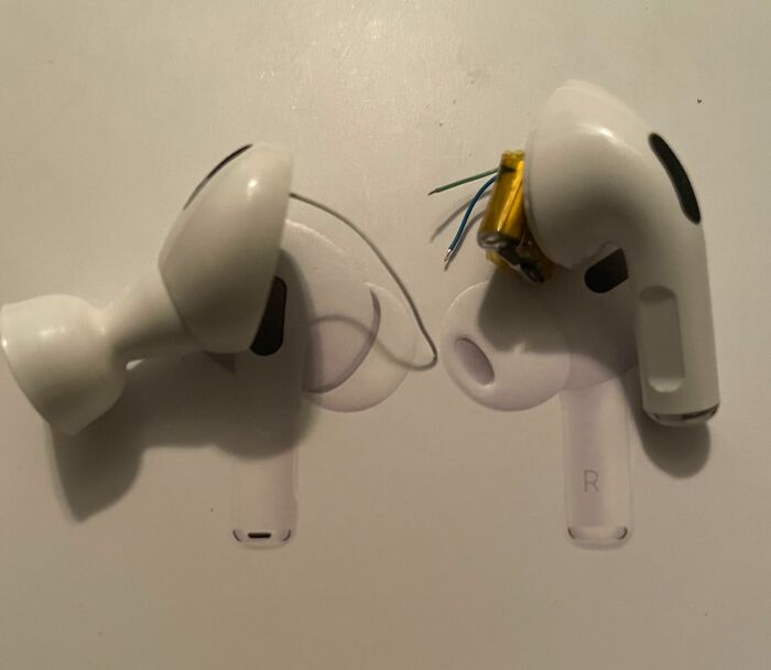 Low-quality earbuds with exposed wires and broken parts on a table.
