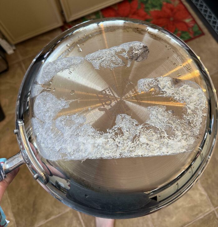 Low-quality items: tarnished stainless steel pan with water stains on a tiled kitchen floor.