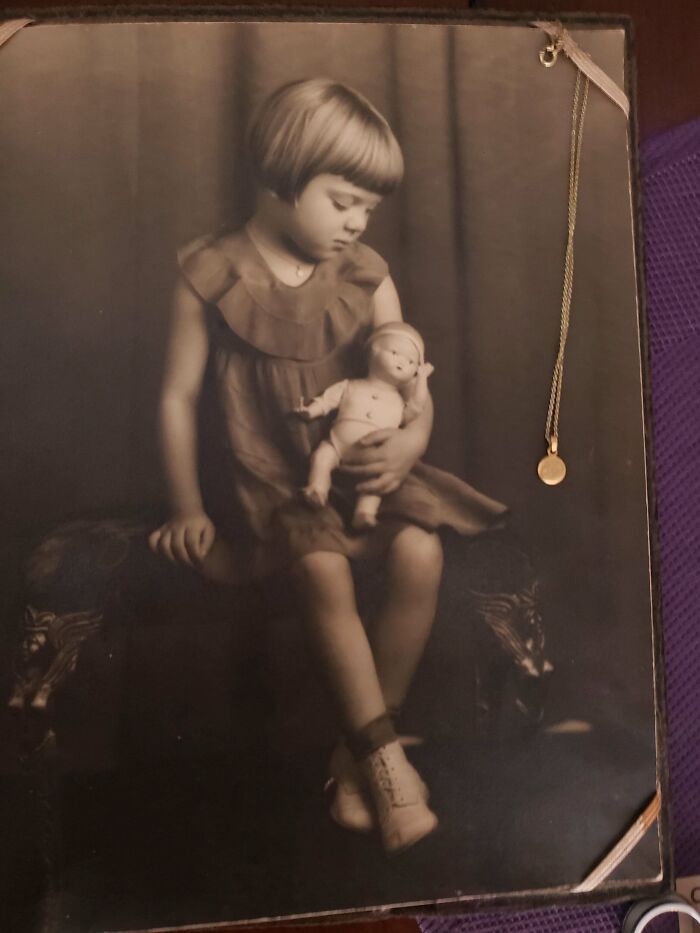 Vintage photo of a young girl holding a doll, showcasing fascinating old images from history.