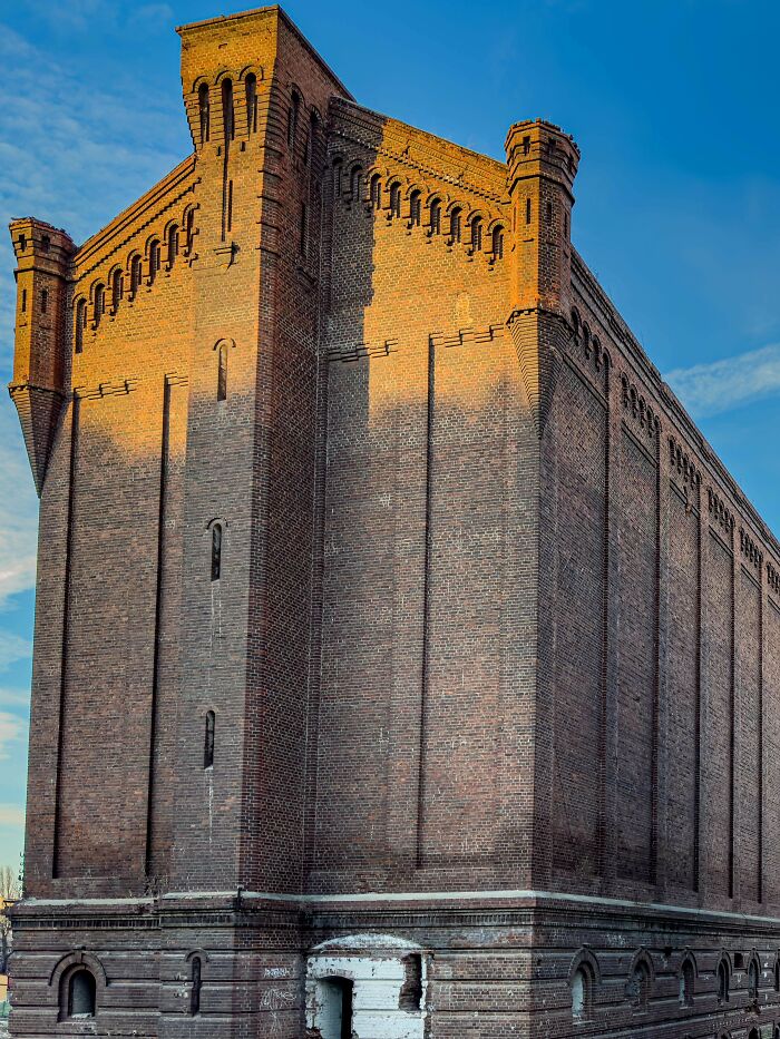 Massive brick building with ominous architecture and narrow windows, exuding an evil aura like a supervillain headquarters.