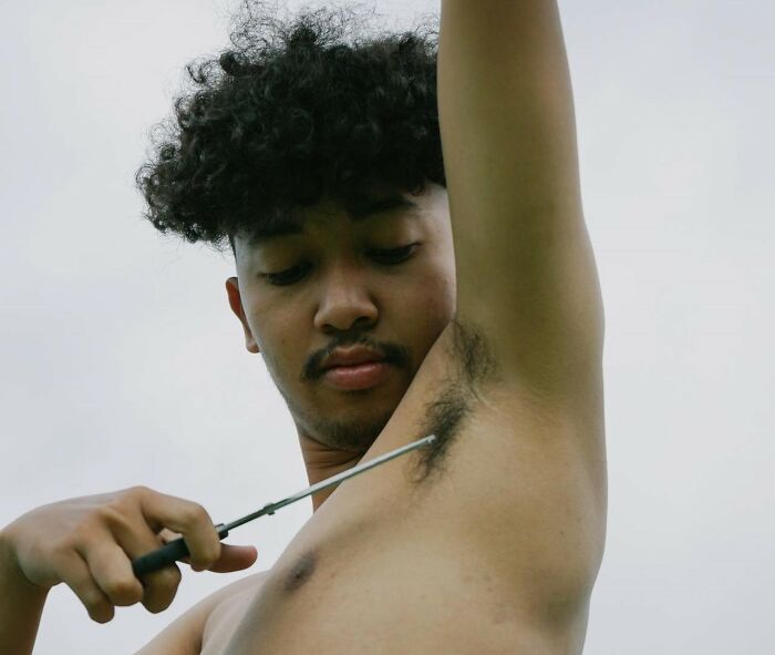 Man trimming armpit hair, highlighting activities men shouldn't be judged for doing.