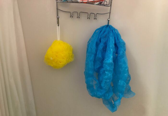 Low-quality items, a yellow bath puff and a blue shower loofah, hanging on a bathroom rack.