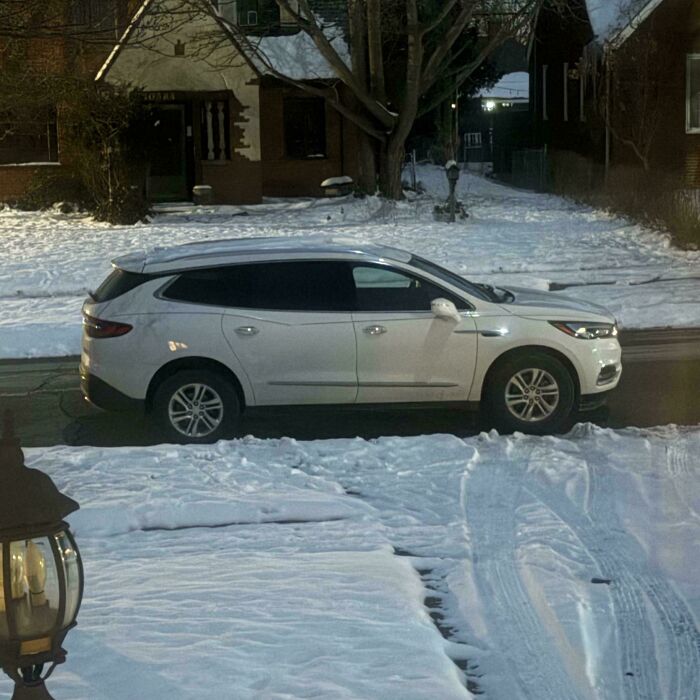 White SUV parked improperly across a snowy driveway, showcasing neighbors being so horrific they had to be shamed.