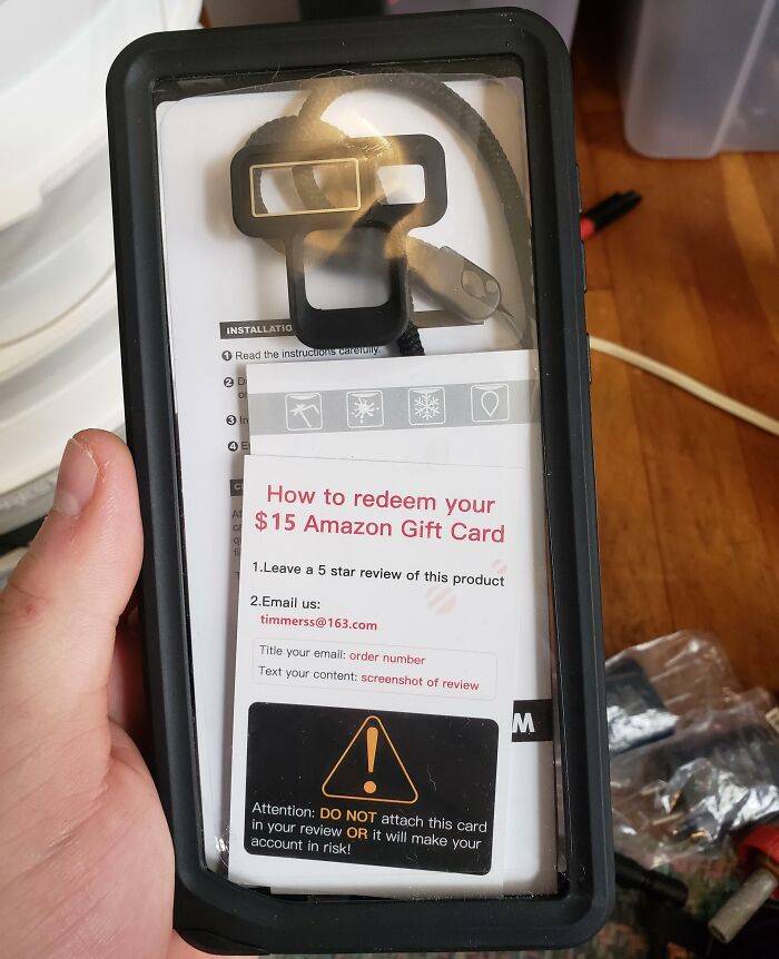 Hand holding a low-quality phone mount with a gift card redemption instruction.