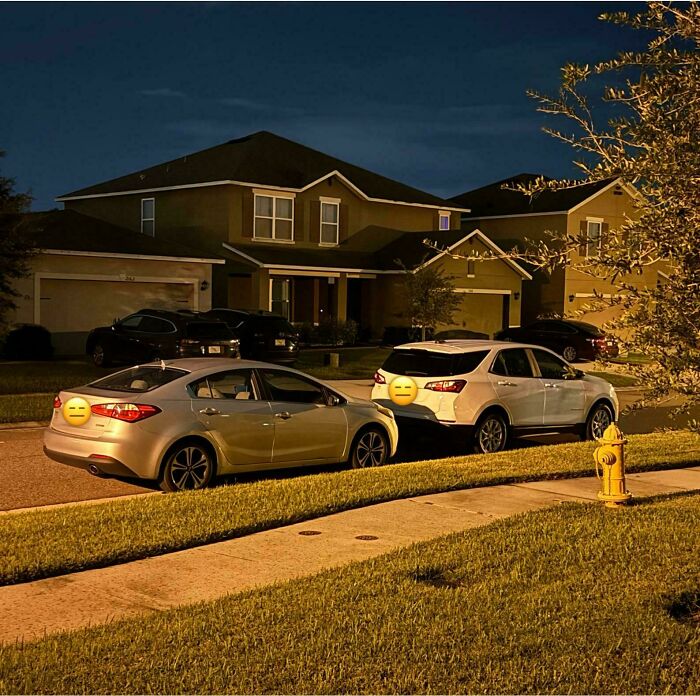 Cars parked tightly on a street at night, reflecting challenges with terrible neighbors in a residential area.